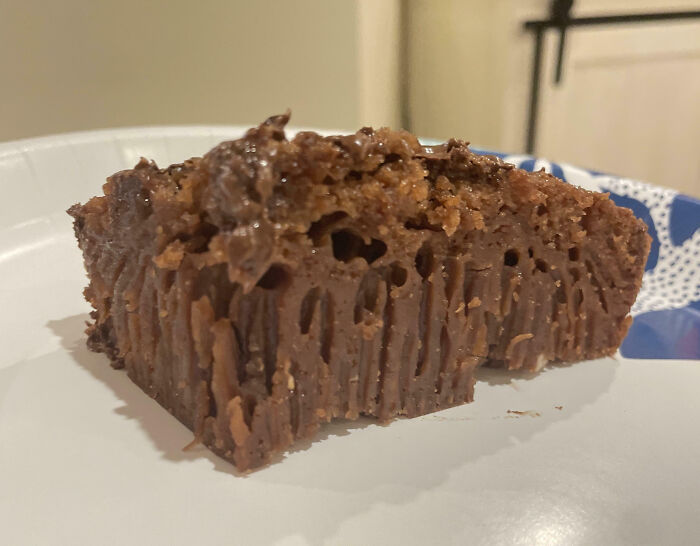 Undercooked and unevenly baked brownie slice on a paper plate, illustrating a cooking fail in the kitchen.