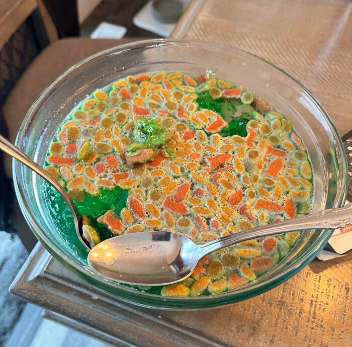 Bowl of green liquid with spoiled moldy cereal inside and two spoons, illustrating a hilarious cooking fail.