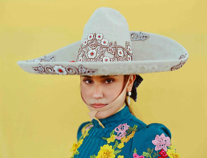 Female rodeo rider in colorful embroidered attire and decorative hat, showcasing the beauty and power of all-female rodeo riders.