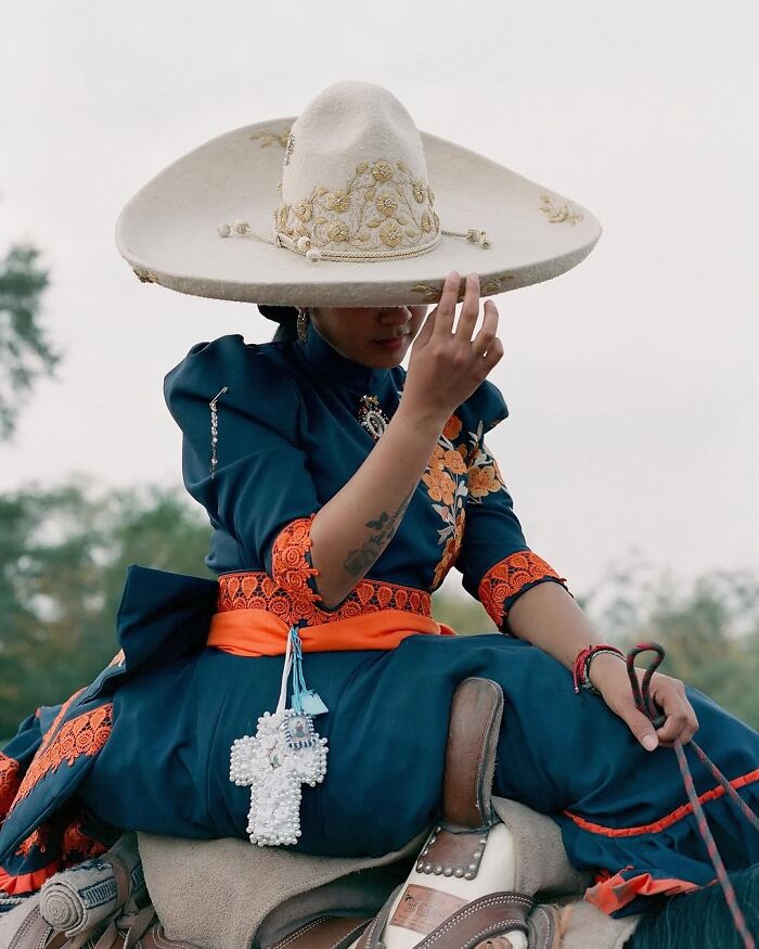 Female rodeo rider wearing traditional attire and large embroidered hat, showcasing the power and beauty of rodeo culture.