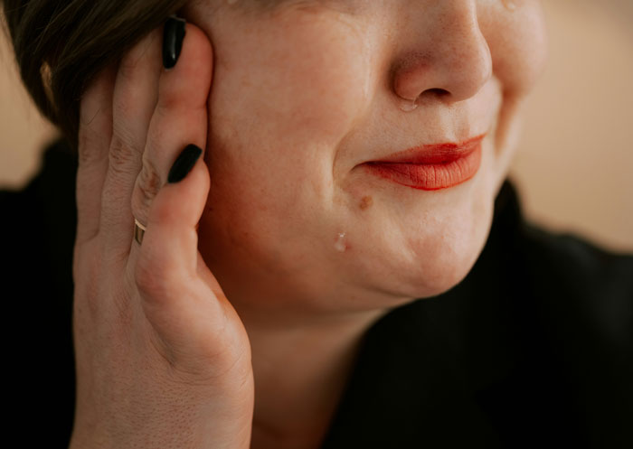 Close-up of a woman with red lipstick gently touching her face, illustrating a woman refusing obese mom babysitting newborn. Close-up of a woman with red lipstick gently touching her face, illustrating a woman refusing obese mom babysitting newborn.