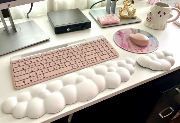 Ergonomic cloud-shaped wrist rests on a desk with a pink keyboard, mouse, and ghost-themed mug for a happy workspace.