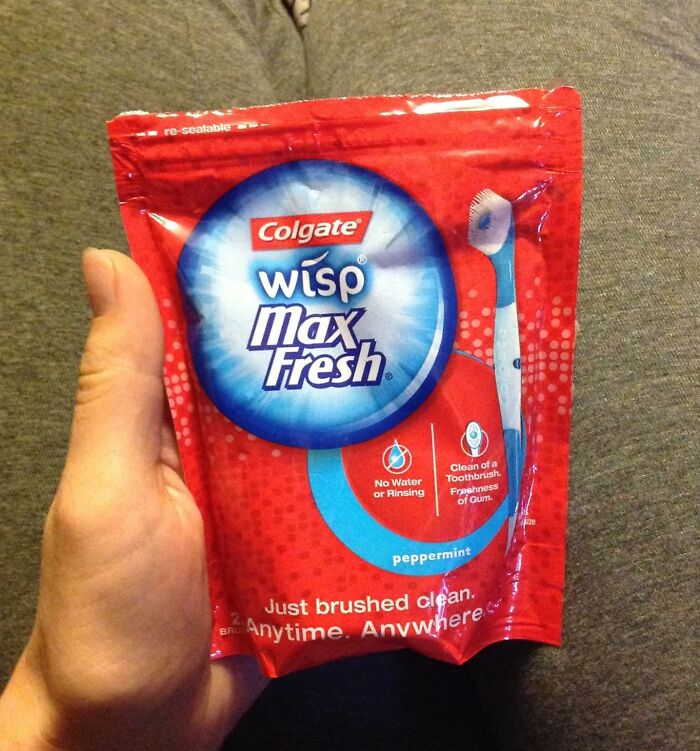 Hand holding Colgate Wisp Max Fresh peppermint, an in-flight essential for a first-class feeling on a coach budget.