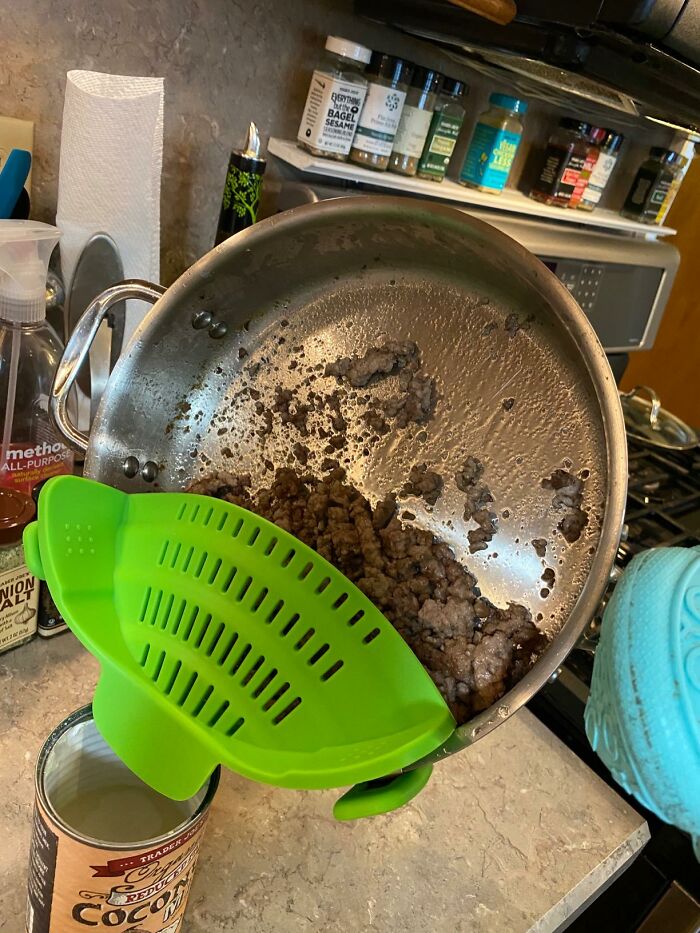 Green silicone strainer used to drain cooked ground meat from a pan, a handy adulting kitchen find.