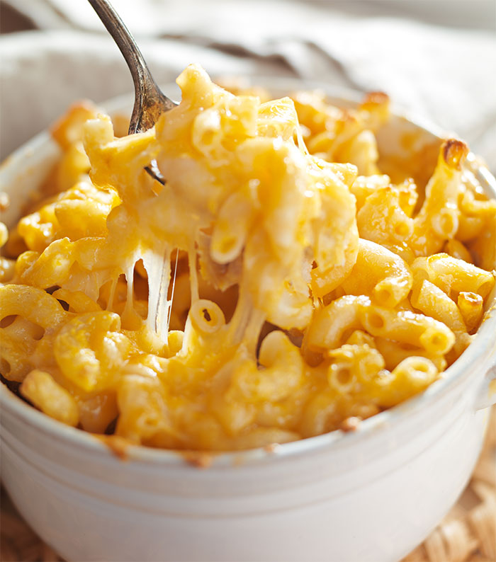 Baked macaroni and cheese with melted cheese being lifted by a fork, illustrating food stealing revenge concept. Baked macaroni and cheese with melted cheese being lifted by a fork, illustrating food stealing revenge concept.