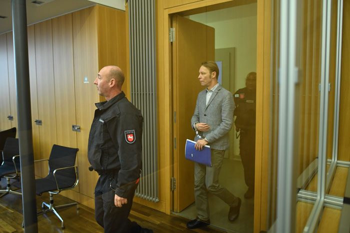 Man suspected in Madeleine McCann case smirks while escorted by security in a courtroom with wooden paneling. Man suspected in Madeleine McCann case smirks while escorted by security in a courtroom with wooden paneling.