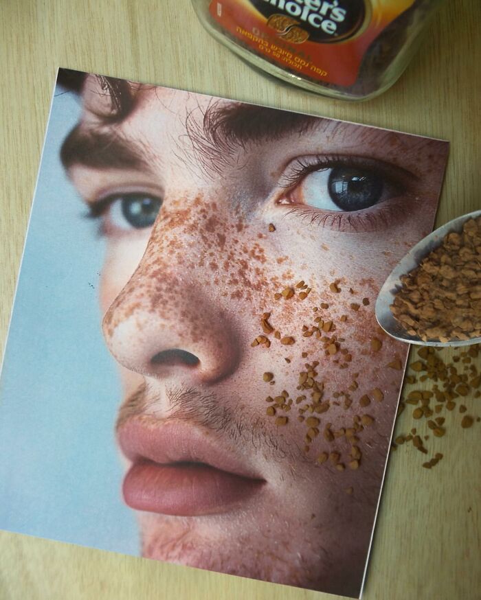 Close-up photo manipulation of a freckled face with coffee granules blending into the skin on a wooden table.