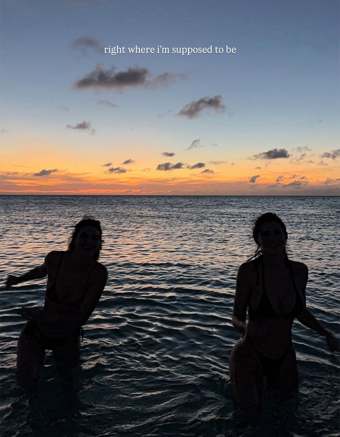Two women walking in shallow ocean water during a colorful sunset, highlighting talent and a beach walk atmosphere. Two women walking in shallow ocean water during a colorful sunset, highlighting talent and a beach walk atmosphere.