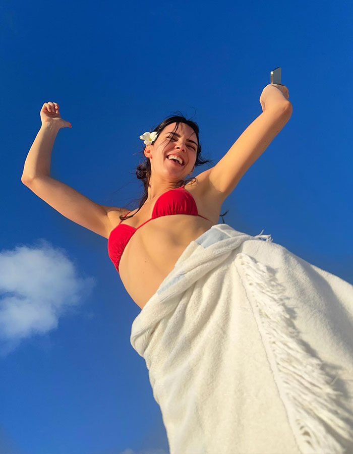 Young woman in a red bikini enjoying a joyful beach walk under a clear blue sky, capturing a lively moment outdoors. Young woman in a red bikini enjoying a joyful beach walk under a clear blue sky, capturing a lively moment outdoors.