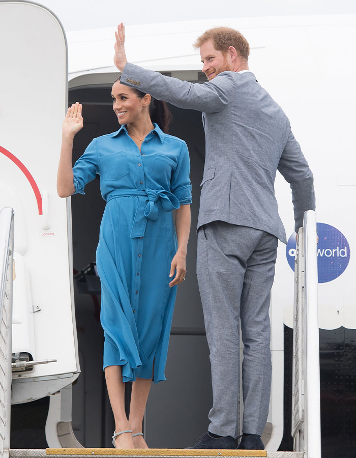 Meghan Markle and Prince Harry waving while boarding an airplane, related to Meghan Markle's note to flight attendant viral story. Meghan Markle and Prince Harry waving while boarding an airplane, related to Meghan Markle's note to flight attendant viral story.