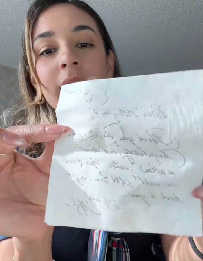 Woman holding handwritten note, illustrating Meghan Markle's note to flight attendant going viral online. Woman holding handwritten note, illustrating Meghan Markle's note to flight attendant going viral online.
