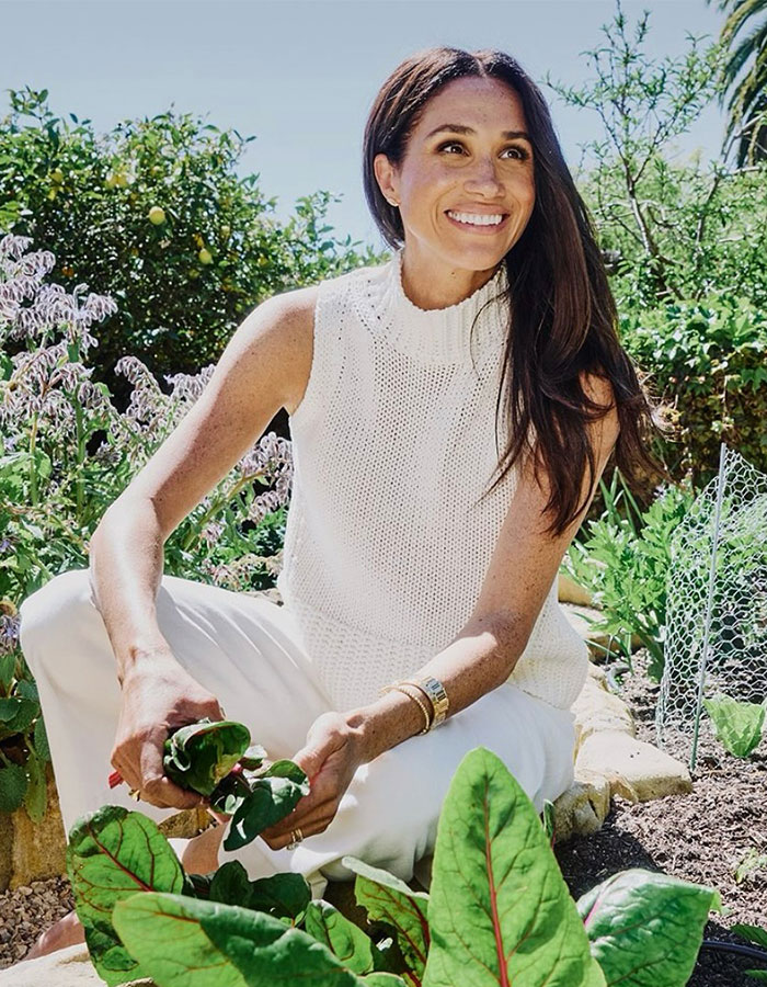 Meghan Markle smiling outdoors in a garden, holding fresh greens, related to Meghan Markle's note to flight attendant viral story. Meghan Markle smiling outdoors in a garden, holding fresh greens, related to Meghan Markle's note to flight attendant viral story.