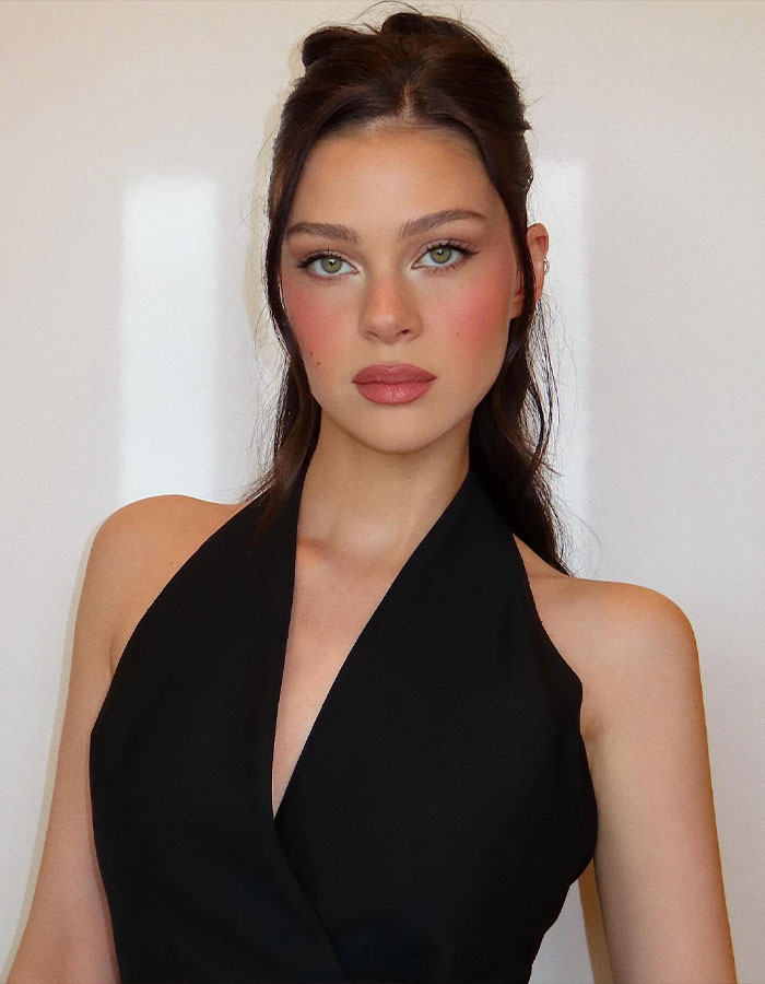 Bella Thorne posing in a black halter top, makeup accentuating her green eyes and soft pink lips against a plain background. Bella Thorne posing in a black halter top, makeup accentuating her green eyes and soft pink lips against a plain background.