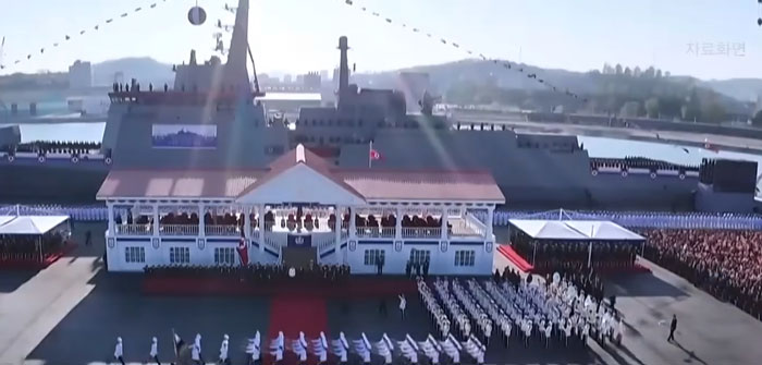 Large 5,000-ton warship docked near a military parade with soldiers assembled and spectators watching on a bright day. Large 5,000-ton warship docked near a military parade with soldiers assembled and spectators watching on a bright day.