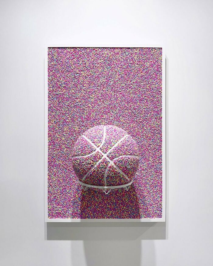 Basketball covered in colorful sprinkles art installation creating a burst of color effect on wall.
