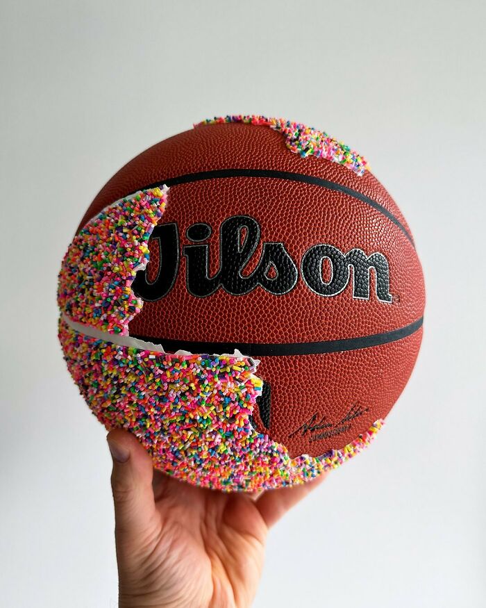 Basketball partially covered in colorful sprinkles held by a hand, showcasing unique sprinkle art by Pepe Bratanov.