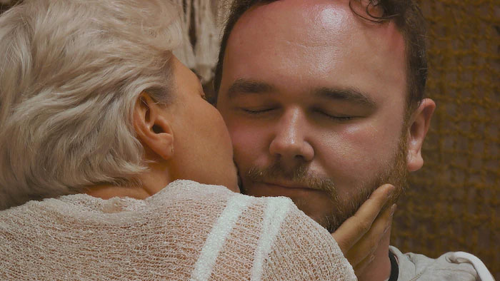 A woman whispering into a man's ear while he closes his eyes in a scene from the reality show Virgin Island. A woman whispering into a man's ear while he closes his eyes in a scene from the reality show Virgin Island.