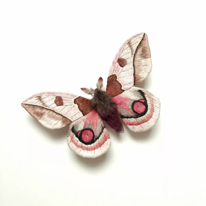 Embroidered fiber moth with pink, brown, and black detailed wings crafted by Yumi Okita on a white background.