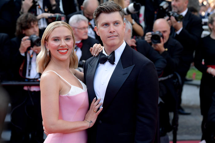 Scarlett Johansson and husband posing on red carpet with photographers in background, referencing SNL roast joke revenge. Scarlett Johansson and husband posing on red carpet with photographers in background, referencing SNL roast joke revenge.