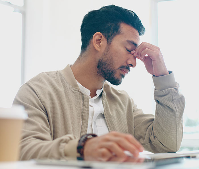 Man frustrated while using laptop, illustrating guy getting petty revenge after Airbnb host jacks up price last minute. Man frustrated while using laptop, illustrating guy getting petty revenge after Airbnb host jacks up price last minute.