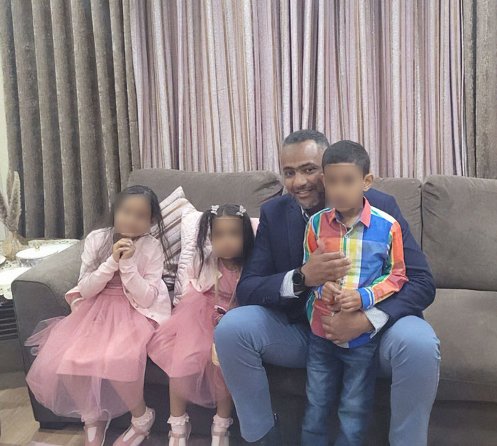 Father of four with few followers sitting on a couch with children, smiling in a home living room setting. Father of four with few followers sitting on a couch with children, smiling in a home living room setting.