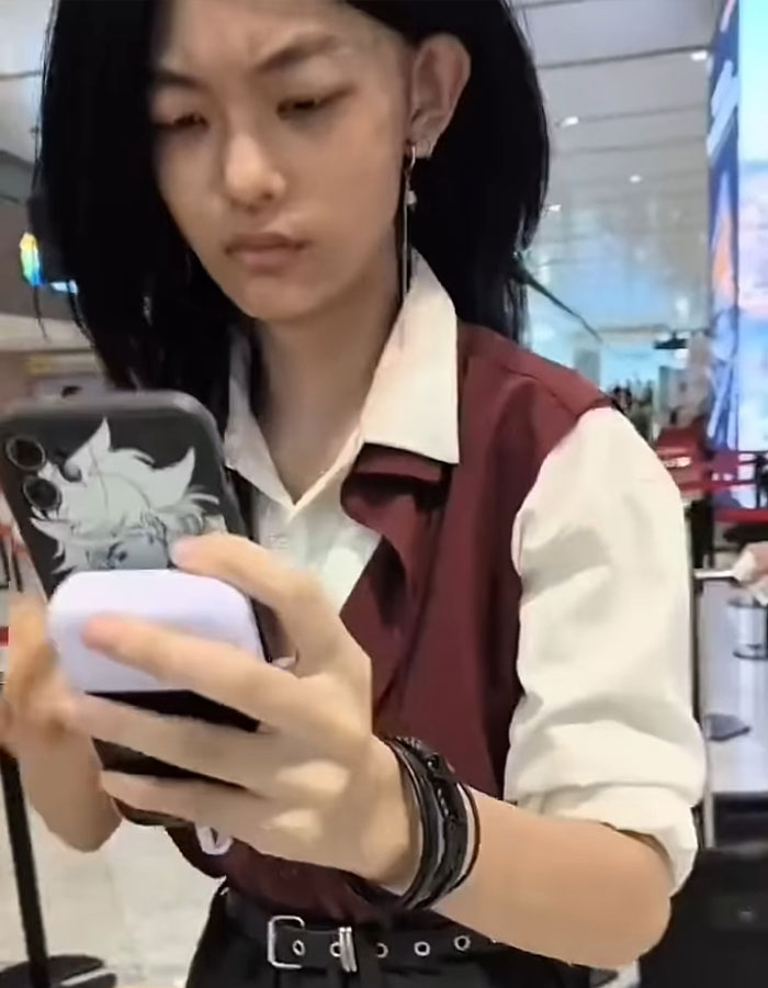 Young passenger at airport checking phone after facial recognition failed, asked to remove makeup during security process Young passenger at airport checking phone after facial recognition failed, asked to remove makeup during security process