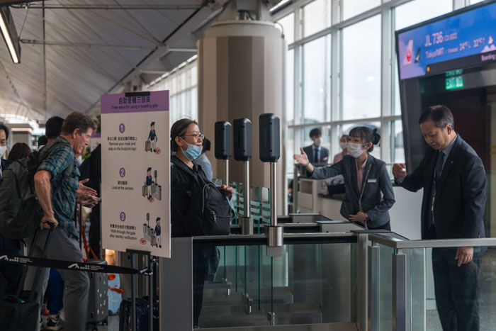 Passenger at airport facial recognition checkpoint with staff assisting after facial recognition failed to recognize her. Passenger at airport facial recognition checkpoint with staff assisting after facial recognition failed to recognize her.