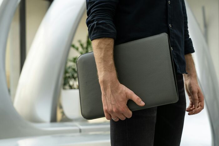 Tech guy holding a laptop case outdoors, symbolizing moments of finding weird or disturbing issues while fixing computers.