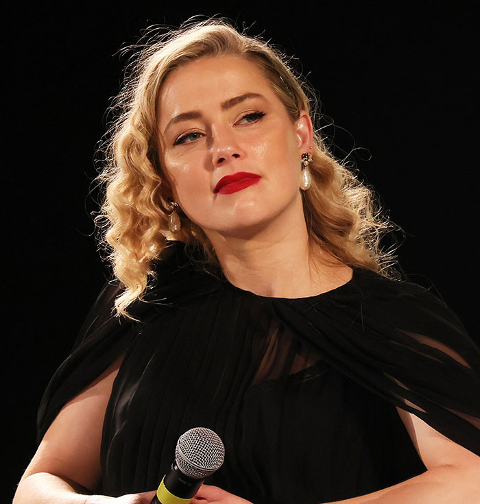 Amber Heard in black dress holding microphone, amid rumors about Elon Musk and new twins paternity claims. Amber Heard in black dress holding microphone, amid rumors about Elon Musk and new twins paternity claims.