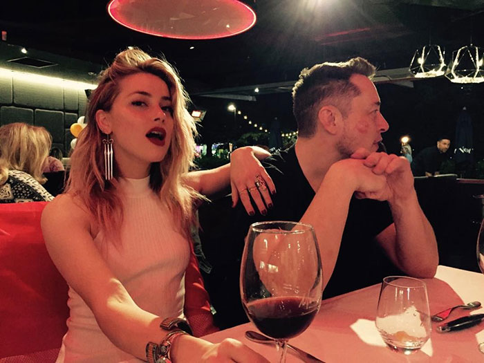 Amber Heard and Elon Musk sitting at a restaurant table with wine glasses, sparking twins paternity rumors. Amber Heard and Elon Musk sitting at a restaurant table with wine glasses, sparking twins paternity rumors.