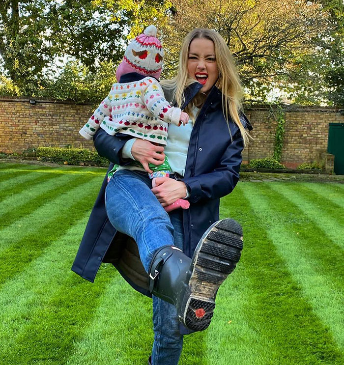 Woman holding child outdoors, playfully lifting leg, representing people convinced Elon Musk fathered Amber Heard's twins. Woman holding child outdoors, playfully lifting leg, representing people convinced Elon Musk fathered Amber Heard's twins.