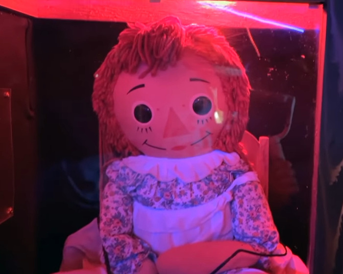 Annabelle doll displayed in a dimly lit case, highlighting the haunted Annabelle doll's chilling history.
