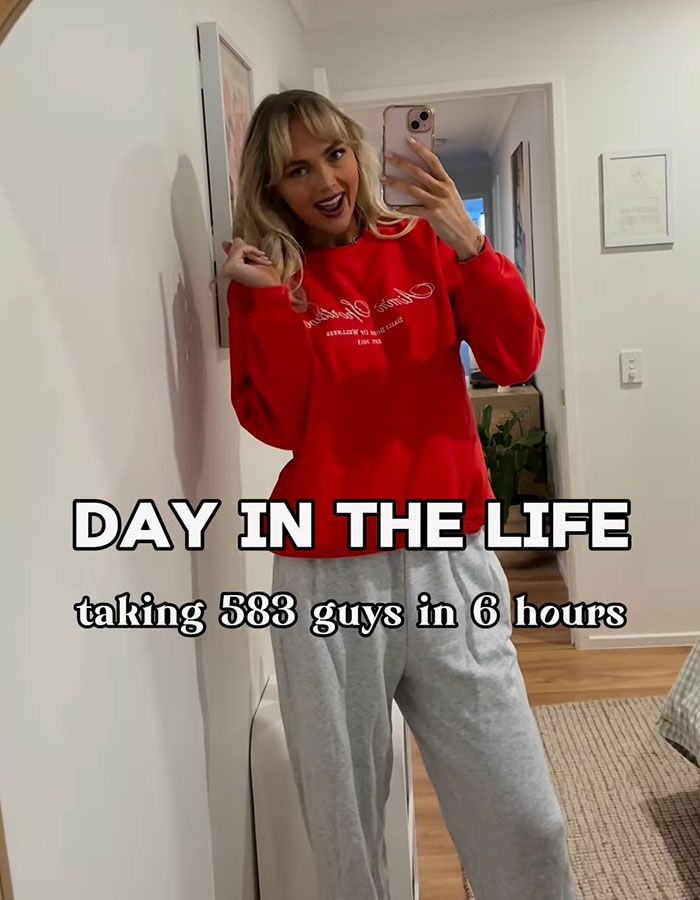 Adult content creator taking selfie wearing red sweatshirt and gray pants in hallway with text about 583 men in 6 hours. Adult content creator taking selfie wearing red sweatshirt and gray pants in hallway with text about 583 men in 6 hours.