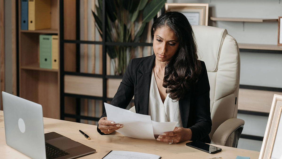 Woman in office looking worried while reviewing documents, illustrating private dating profile exposed by coworker.