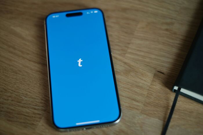 Smartphone displaying Tumblr app on wooden table, illustrating people share companies bad list digital platform access.