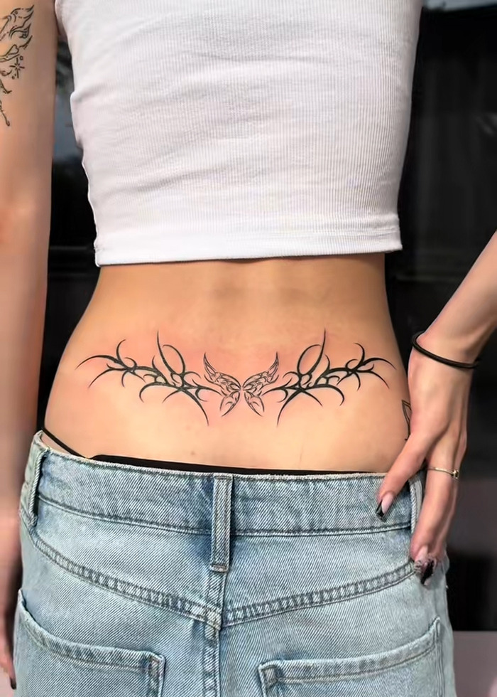 Lower back tattoo with butterfly and tribal design, illustrating the tattoo boom and expert insight on cooling off in 2025. Lower back tattoo with butterfly and tribal design, illustrating the tattoo boom and expert insight on cooling off in 2025.