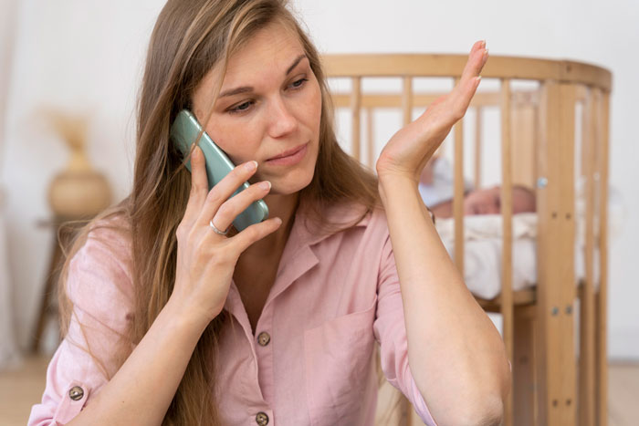 Young woman in pink shirt on phone, looking frustrated while caring for two kids at home alone for days Young woman in pink shirt on phone, looking frustrated while caring for two kids at home alone for days