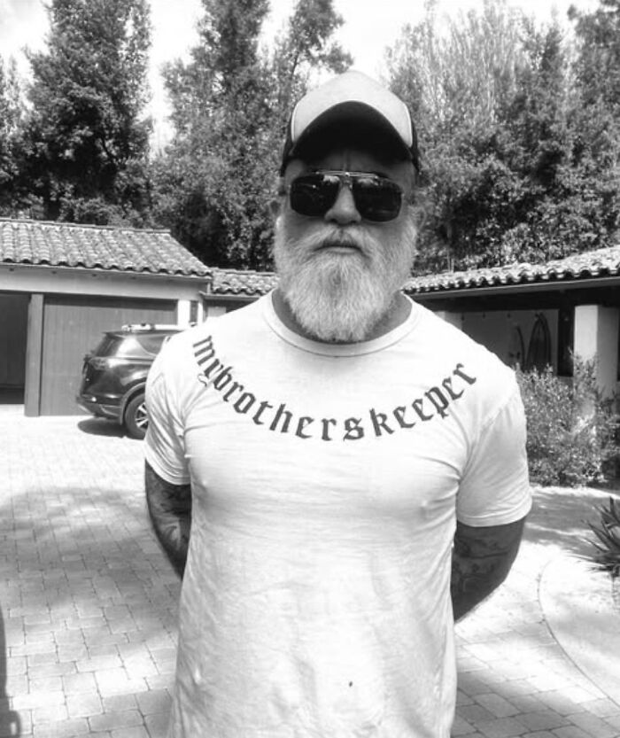 Prison Break star Dominic Purcell with a full white beard, sunglasses, and a cap in an outdoor driveway setting. Prison Break star Dominic Purcell with a full white beard, sunglasses, and a cap in an outdoor driveway setting.