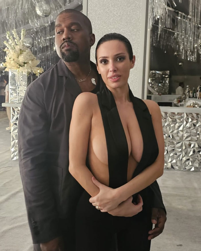 Kanye West with Bianca Censori in a stylish setting, Bianca wearing a revealing black outfit. Kanye West with Bianca Censori in a stylish setting, Bianca wearing a revealing black outfit.