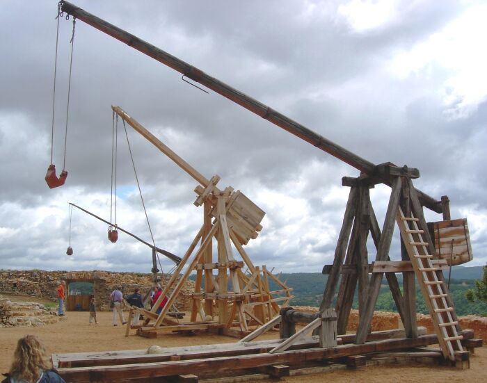 Medieval siege weapons on display under a cloudy sky representing bizarre historical events from the past.