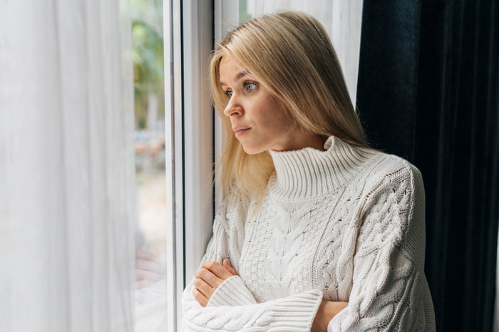 Woman in white sweater looking out window thoughtfully amid neighbor’s kid turning fence into fast food window for dogs. Woman in white sweater looking out window thoughtfully amid neighbor’s kid turning fence into fast food window for dogs.