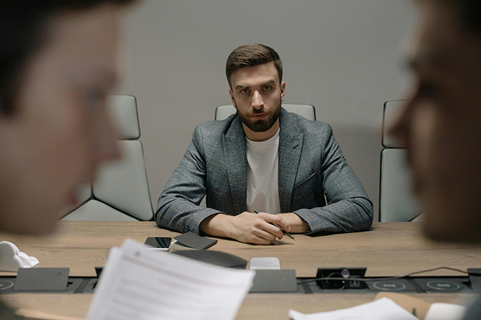 Man playing it by the book during a tense office meeting amid bullying claims from his boss by asking questions Man playing it by the book during a tense office meeting amid bullying claims from his boss by asking questions