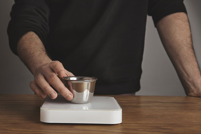 Man placing a small metal container on a digital scale, illustrating a secret scale measuring number twos concept. Man placing a small metal container on a digital scale, illustrating a secret scale measuring number twos concept.