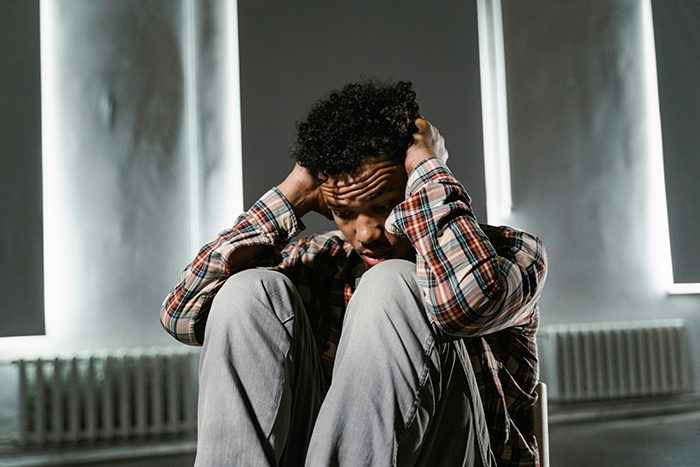 Young man sitting with hands on head, looking distressed after joking proposal was taken seriously by girlfriend. Young man sitting with hands on head, looking distressed after joking proposal was taken seriously by girlfriend.