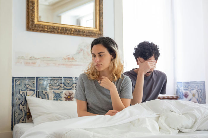 Couple in an open relationship sitting on bed looking upset, highlighting hypocrisy and emotional conflict. Couple in an open relationship sitting on bed looking upset, highlighting hypocrisy and emotional conflict.