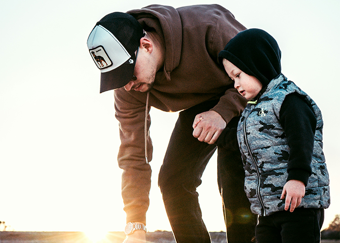 Man watching over child outdoors at sunset, showing the challenge of caring for kids during a family trip experience. Man watching over child outdoors at sunset, showing the challenge of caring for kids during a family trip experience.