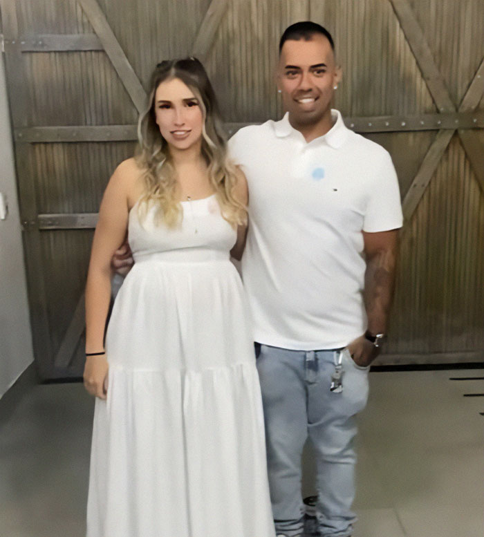Couple in white clothing posing indoors during a baby's gender reveal event sparking a heated debate. Couple in white clothing posing indoors during a baby's gender reveal event sparking a heated debate.