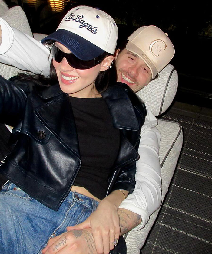 Couple wearing caps and casual clothes, smiling and sitting closely, reflecting a moment at David Beckham's birthday party feud. Couple wearing caps and casual clothes, smiling and sitting closely, reflecting a moment at David Beckham's birthday party feud.