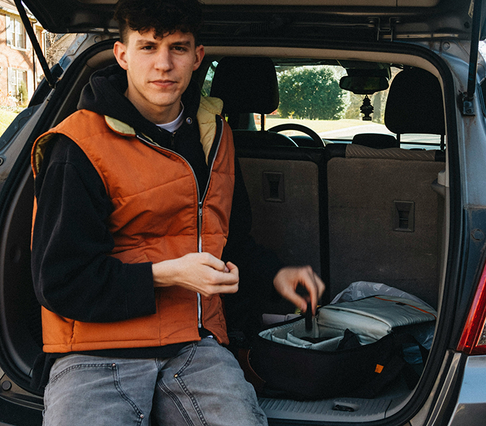 Young man in casual clothes sitting in the trunk of a car, looking tired, symbolizing burned out uncle refusing babysitting. Young man in casual clothes sitting in the trunk of a car, looking tired, symbolizing burned out uncle refusing babysitting.