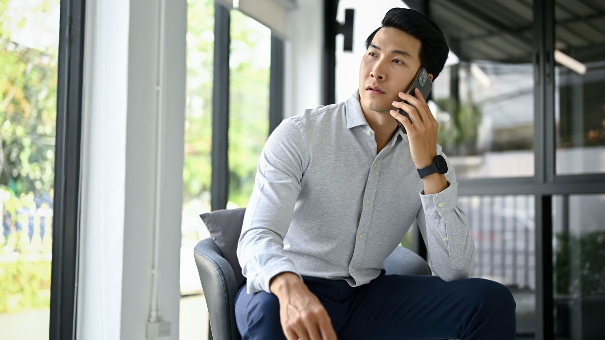 Man calling an ambulance while sitting indoors, showing concern over coworkeru2019s health problems and panic reaction.